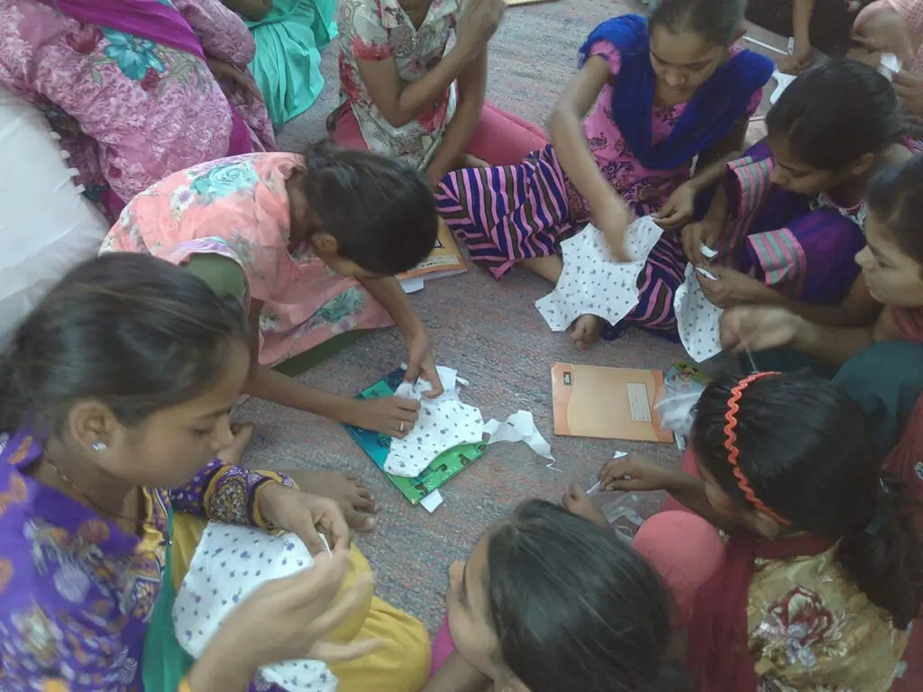 Adolescent girls sitting on the floor working with cloth