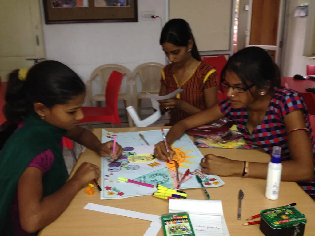 Girls drawing and colouring charts at a table
