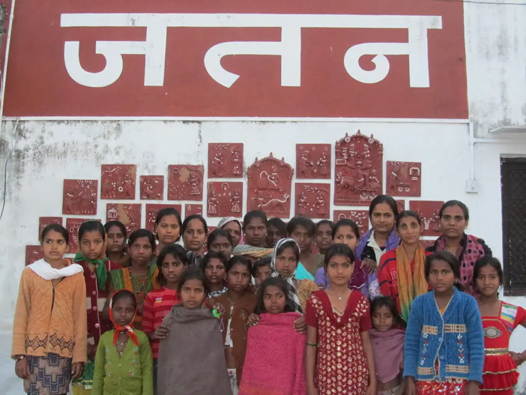 Children standing in front of a wall painted with the word Jatan